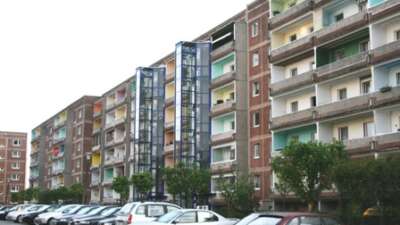 Reihen von Wohnblöcken mit bunter Fassade und geparkten Autos in einer Großstadtstraße.