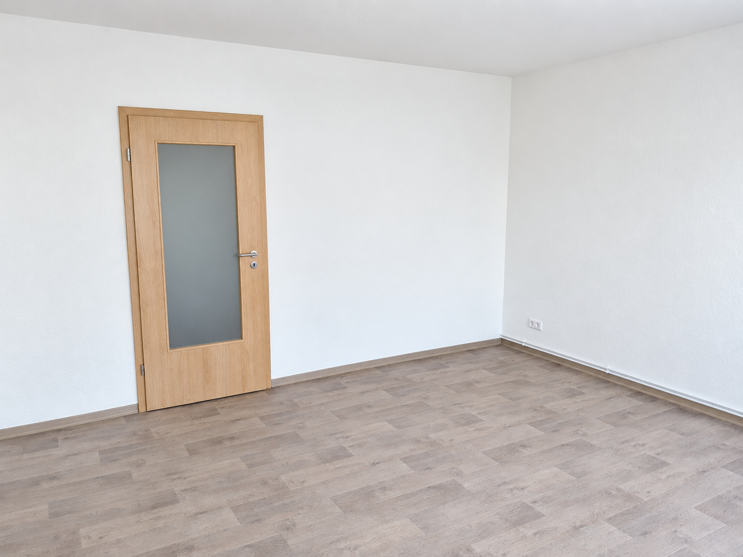 Leerer Raum mit Laminatboden und Holztür, weiße Wände, modernes Interieur.