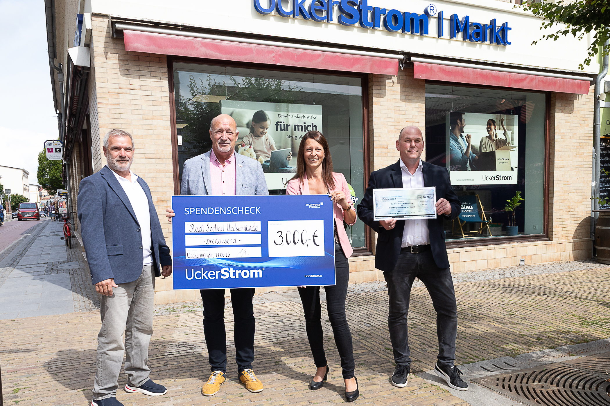 Gruppenfoto vor UckerStrom-Gebäude mit symbolischem Scheck über 3000 Euro an Stadt Schwedt überreicht.